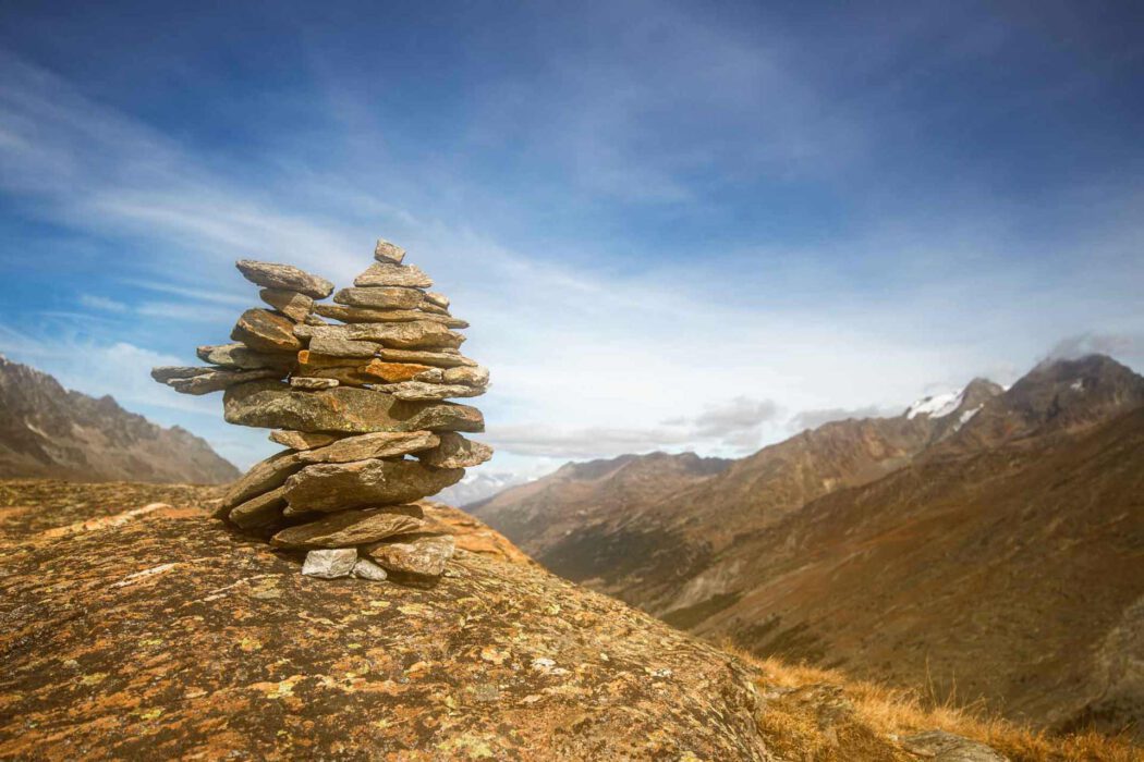 Steinhaufen (Cairn) in den Schweizer Alpen mit Bergpanorama