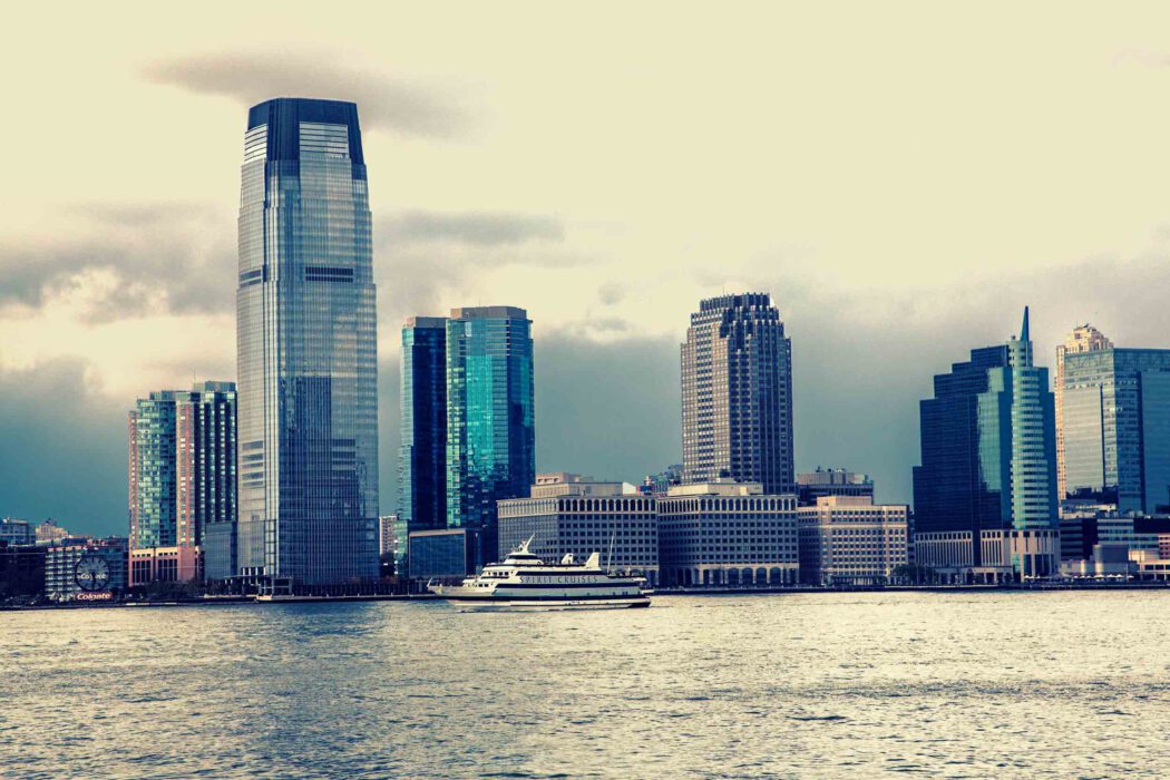 Skyline von Jersey City am Hudson River mit dem Goldman Sachs Tower und einem Spirit Cruises Schiff im Vordergrund, Blick von Manhattan.