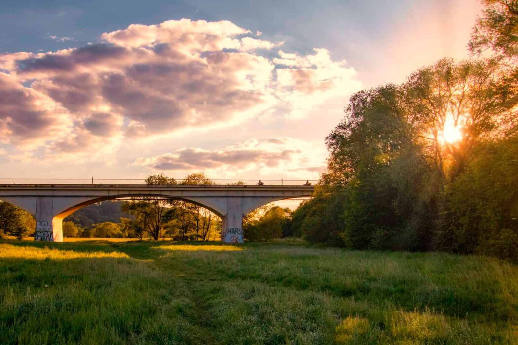 Kemnader Brücke bei Sonnenuntergang über einem grünen Feld mit Bäumen