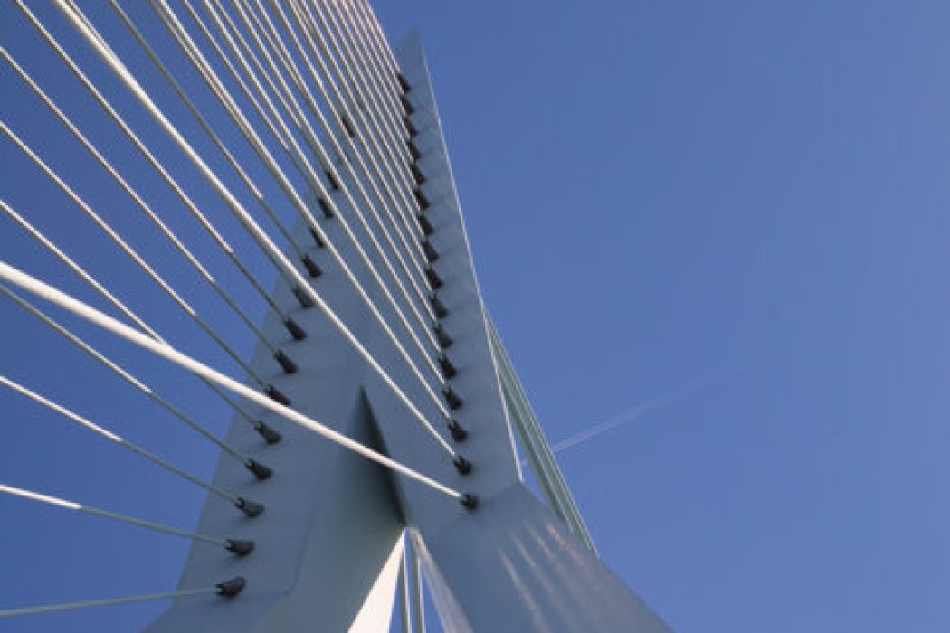 Reisefotografie Rotterdam Erasmusbrücke Detail: Weißer Pylon der Erasmusbrug aus Froschperspektive, weiße Stahlseile gegen tiefblauen Himmel, grafische Architekturaufnahme, Sonnenlicht und Schatten.