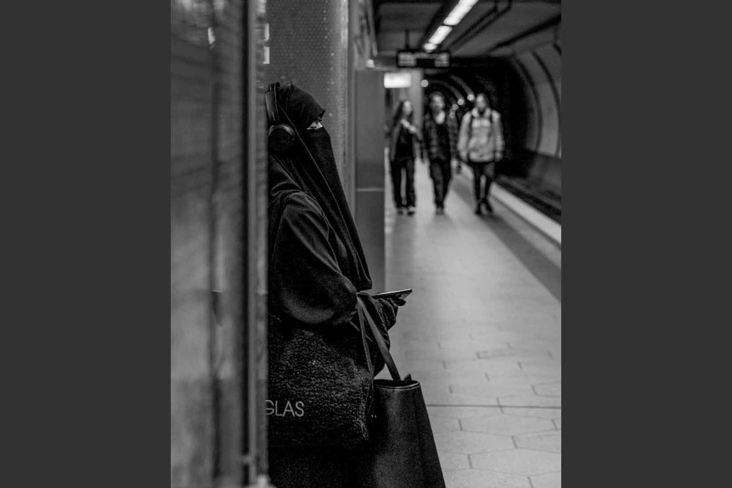 Person mit Kopfhörern und Smartphone in urbaner Umgebung.