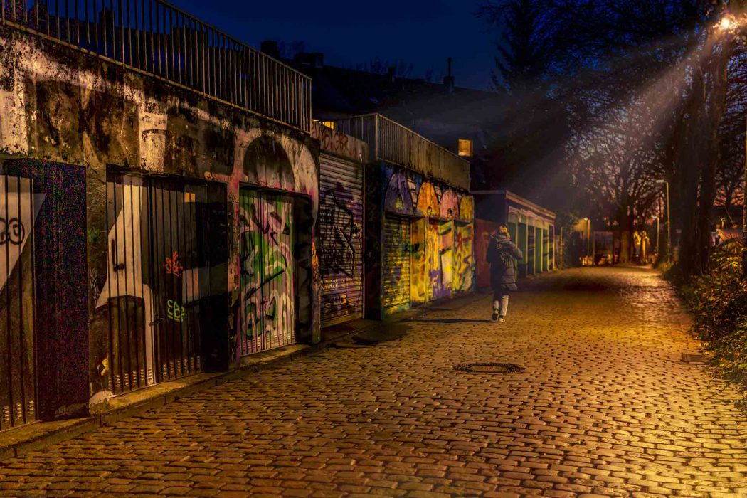 Graffiti Alley bei Nacht mit Kopfsteinpflaster und Person