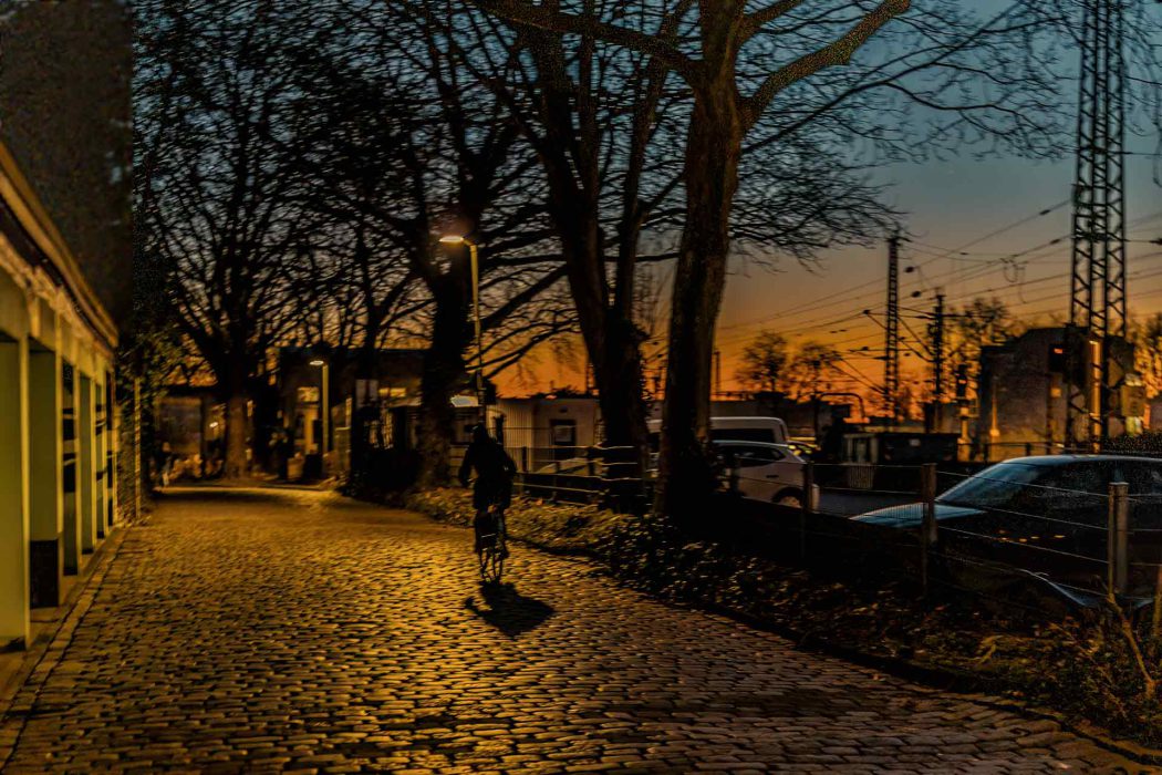 Radfahrer auf Kopfsteinpflasterstraße bei Sonnenuntergang