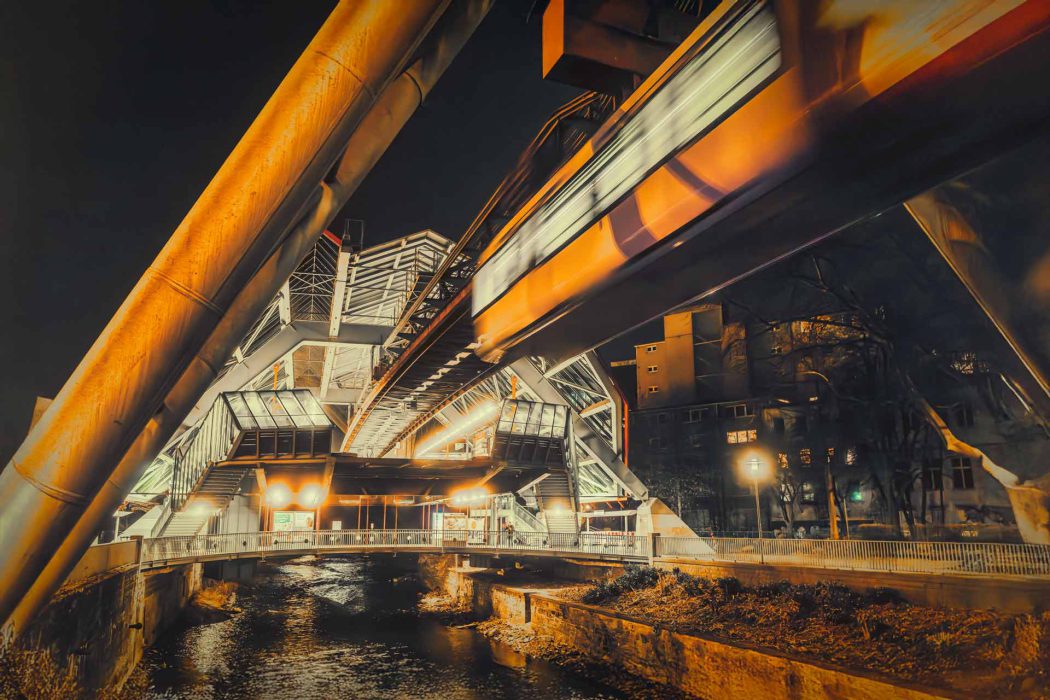Wuppertaler Schwebebahn bei Nacht über einem Fluss.