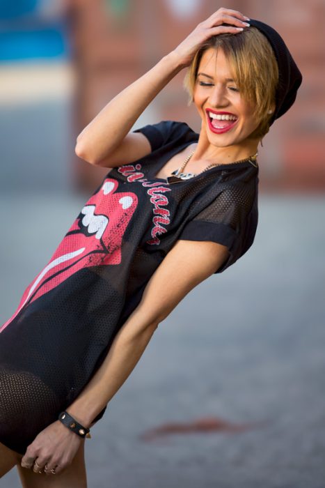Lachende Frau mit blonden Haaren, schwarzem Beanie und Rolling Stones T-Shirt